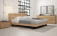 A modern bedroom features a cream upholstered bed centered between two wooden nightstands with lamps against a green wall.