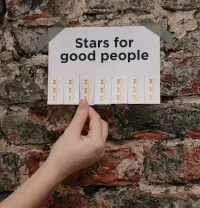 A hand pulls a tear-off tab from a sign on a brick wall that reads