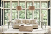 A bright living room with tall windows covered by striped roller shades and patterned floor-length curtains.