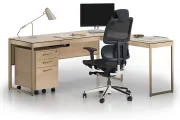 A modern, minimalist home office featuring a V-shaped glass desk, black office chair, and two open, angular bookshelves.