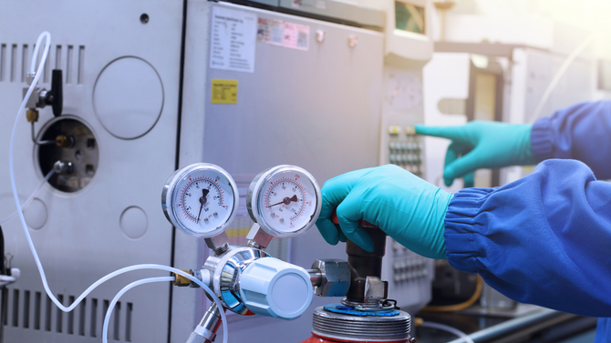A person wearing gloves is working on a machine in a lab.
