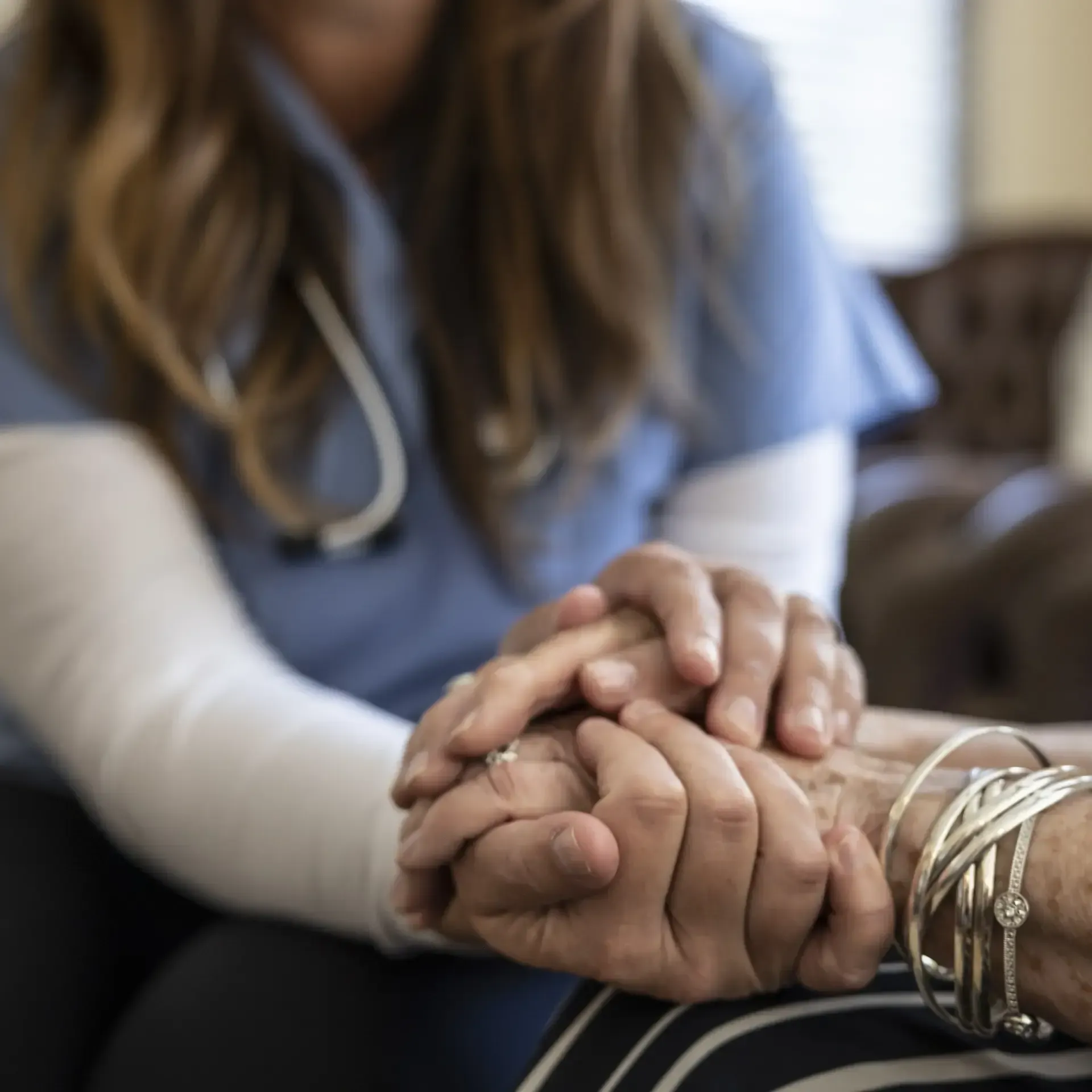 A nurse is holding the hand of an elderly woman