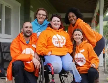 A group of people are posing for a picture with a woman in a wheelchair.