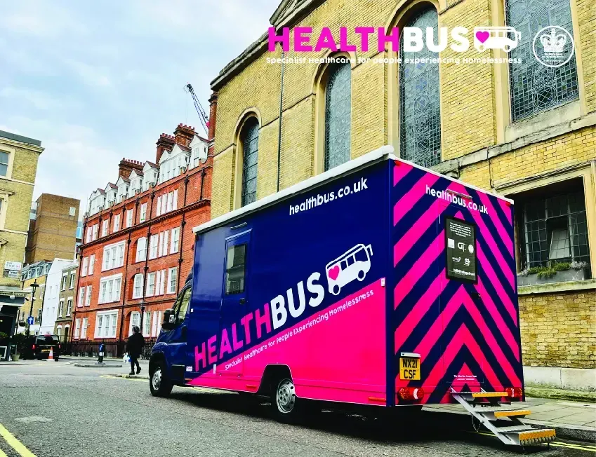 A pink and blue health bus is parked on the side of the road.