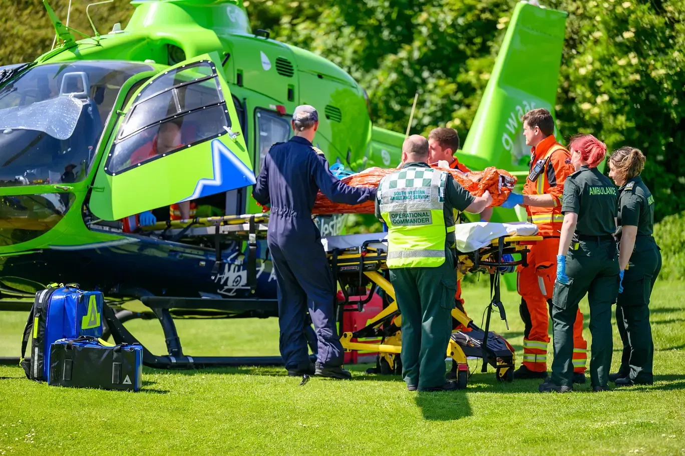 A group of paramedics are carrying a person on a stretcher to a helicopter.