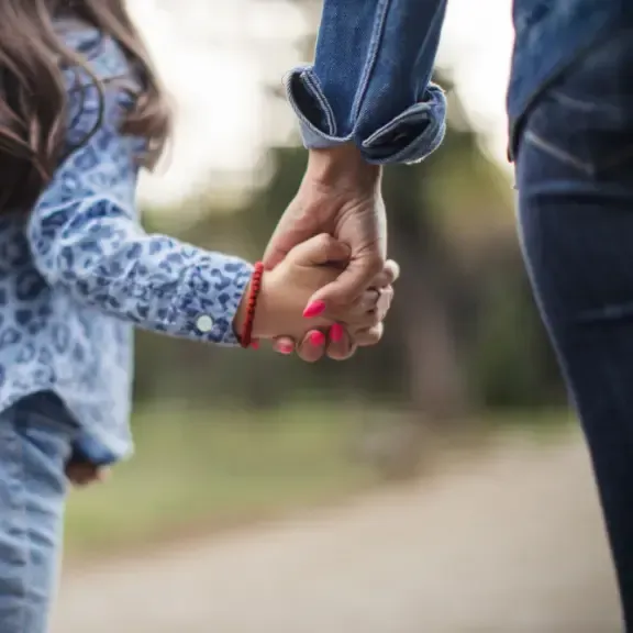 A woman and a little girl are holding hands.