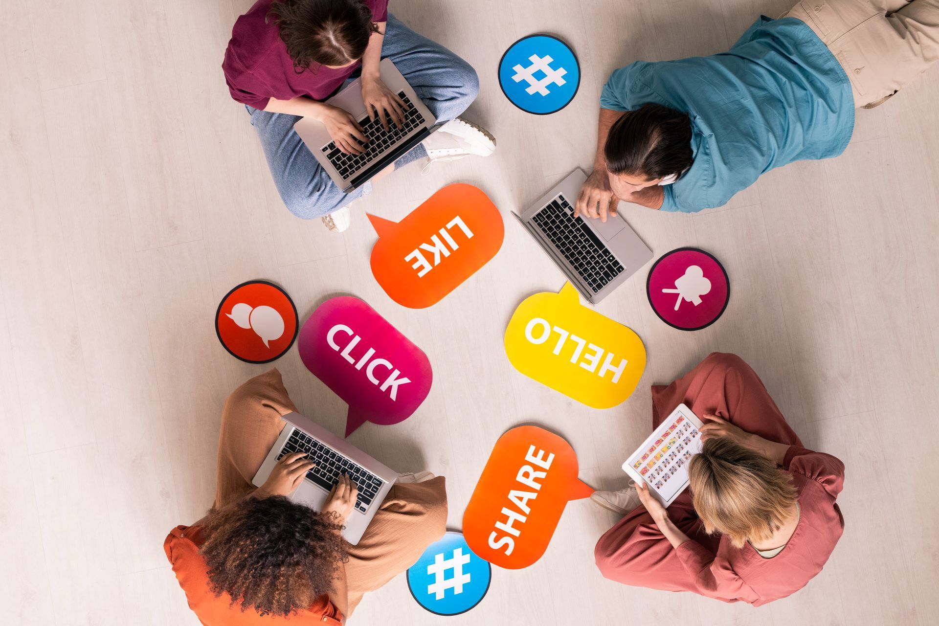 A group of people are sitting on the floor using laptops.