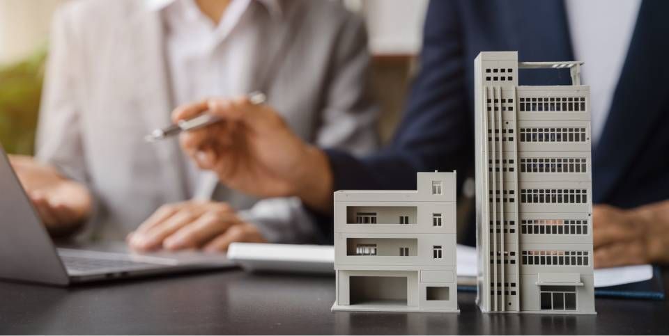 Business meeting with laptop, blurred person, and small model buildings on a desk