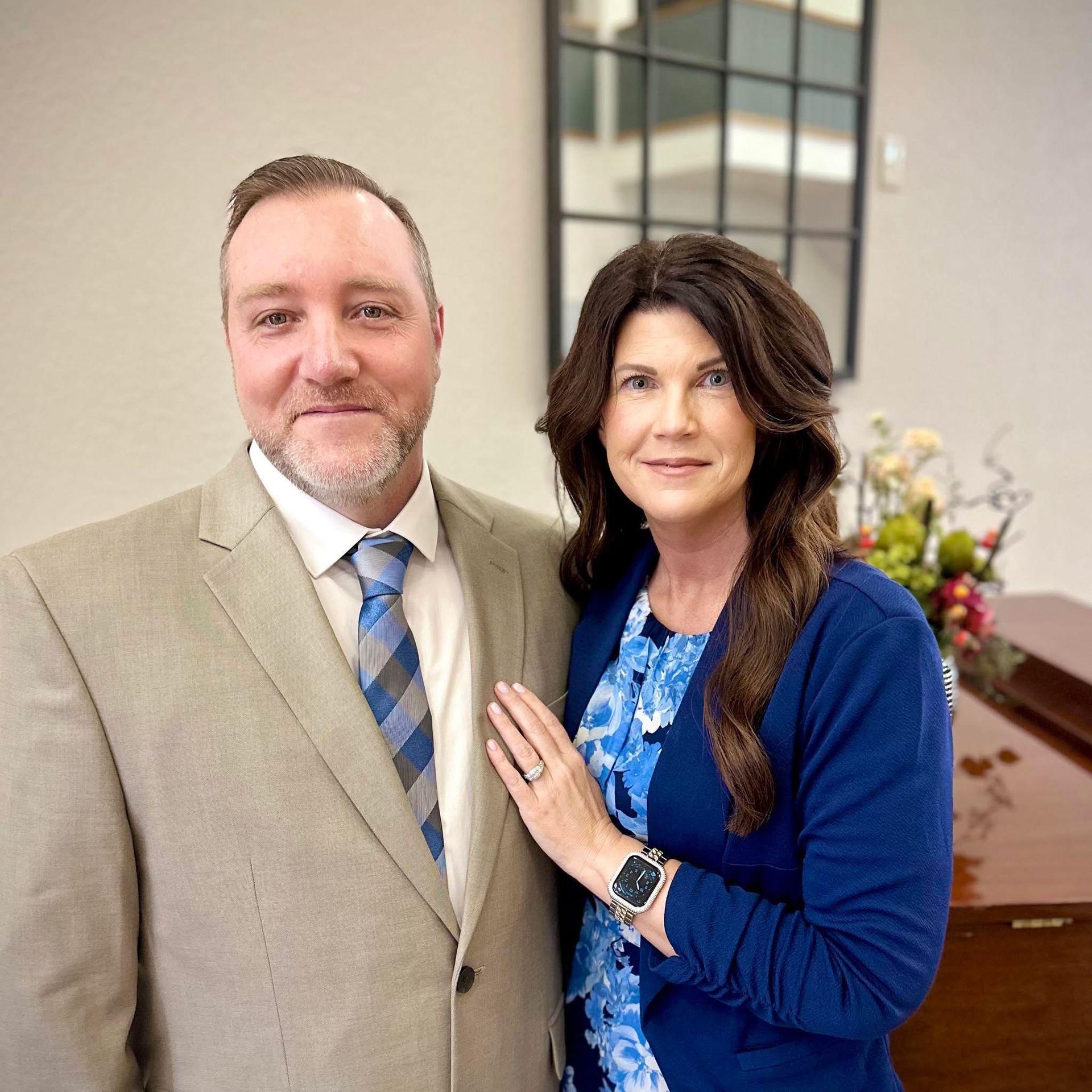 man in a suite standing with a lady in a blue dress