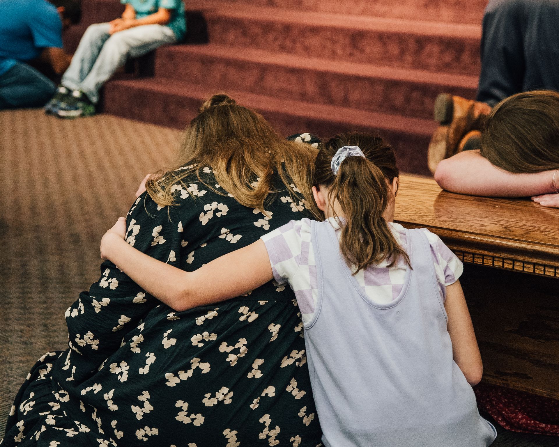 A group of people are kneeling down with their arms around each other