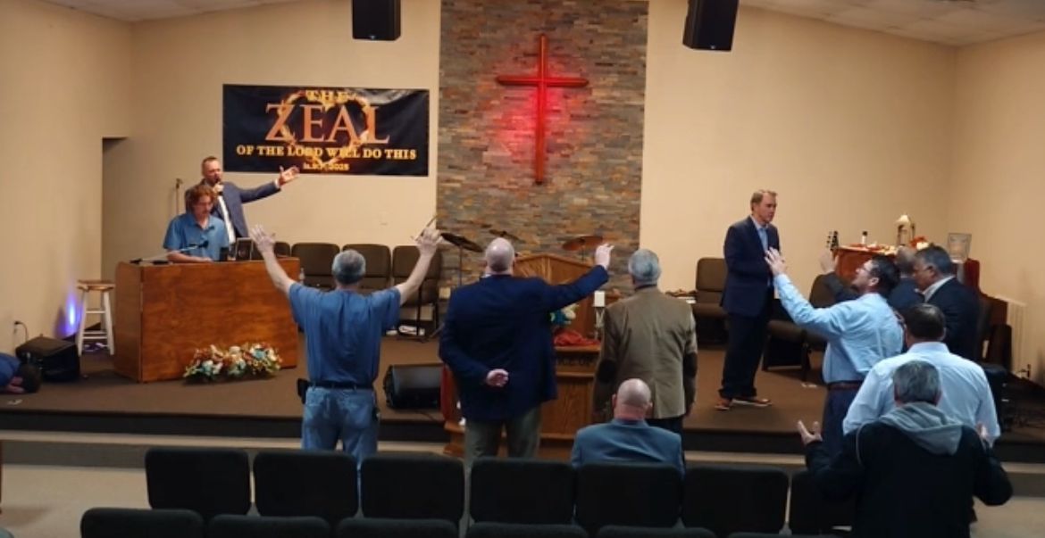 men with uplifted hands and man at piano