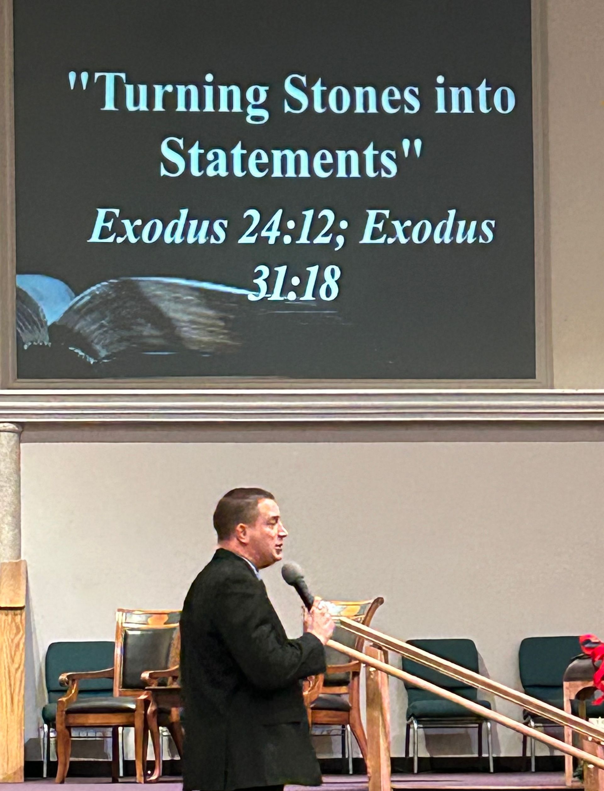 gentle man speaking in front of screens stating 