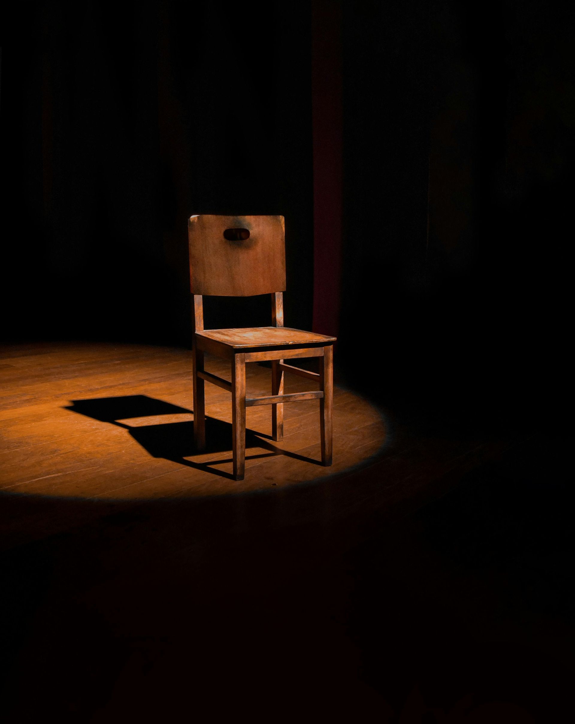 one chair sitting in the spotlight on stage