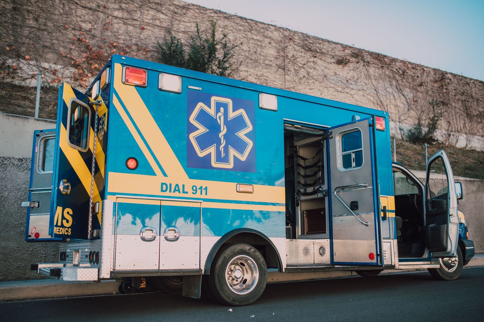 blue emergency ambulance in front of a brick wall