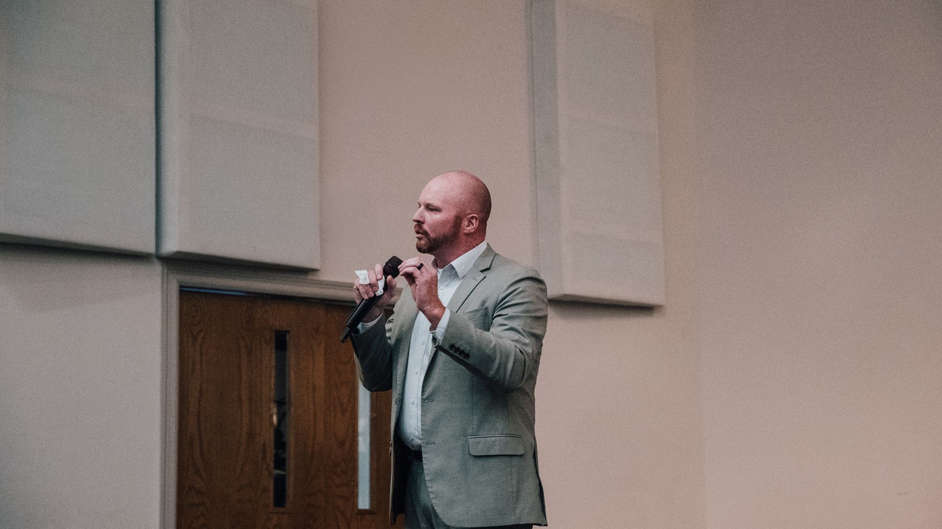 A man in a suit is standing in front of a microphone.