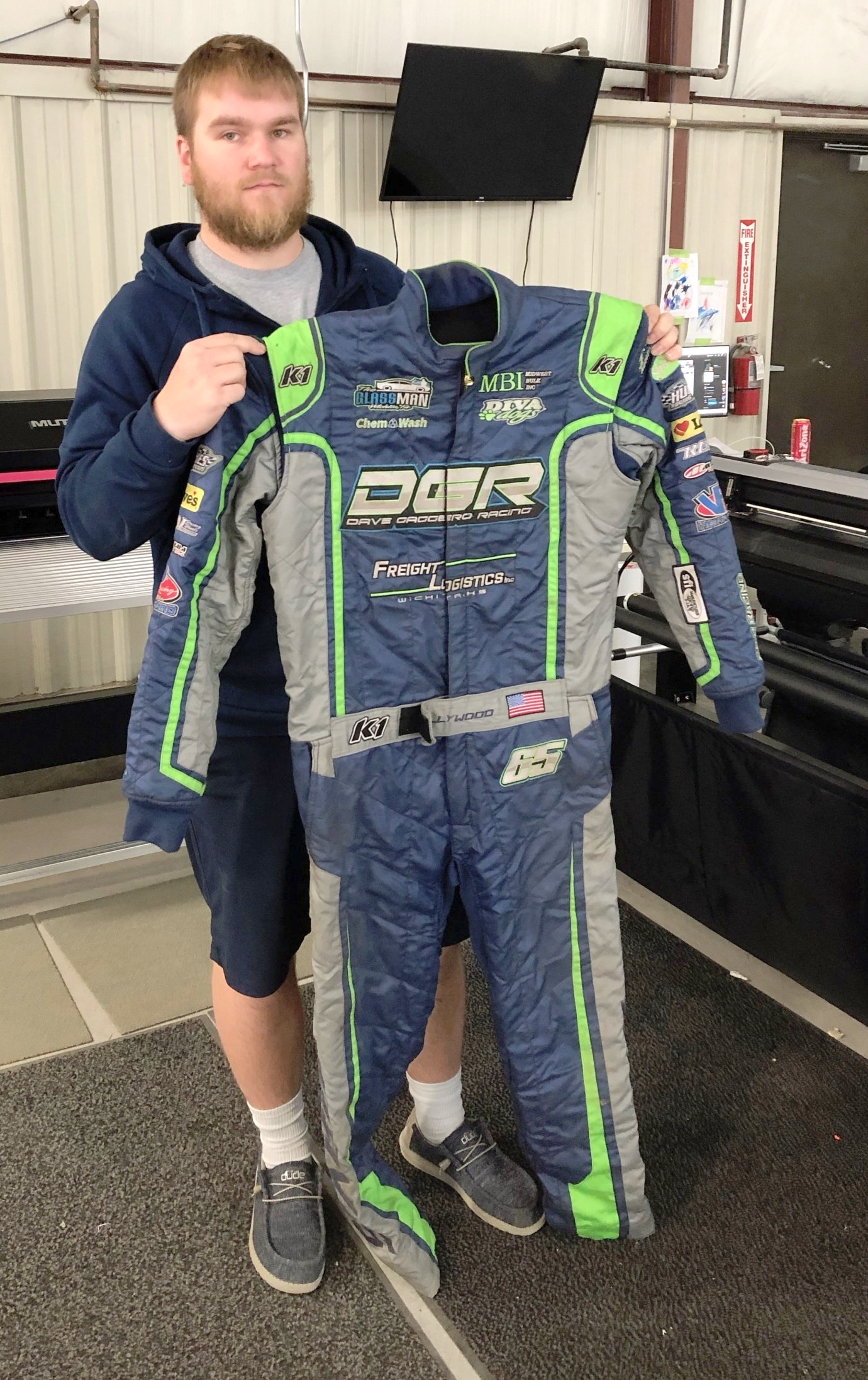 A man holding a printed racing suit