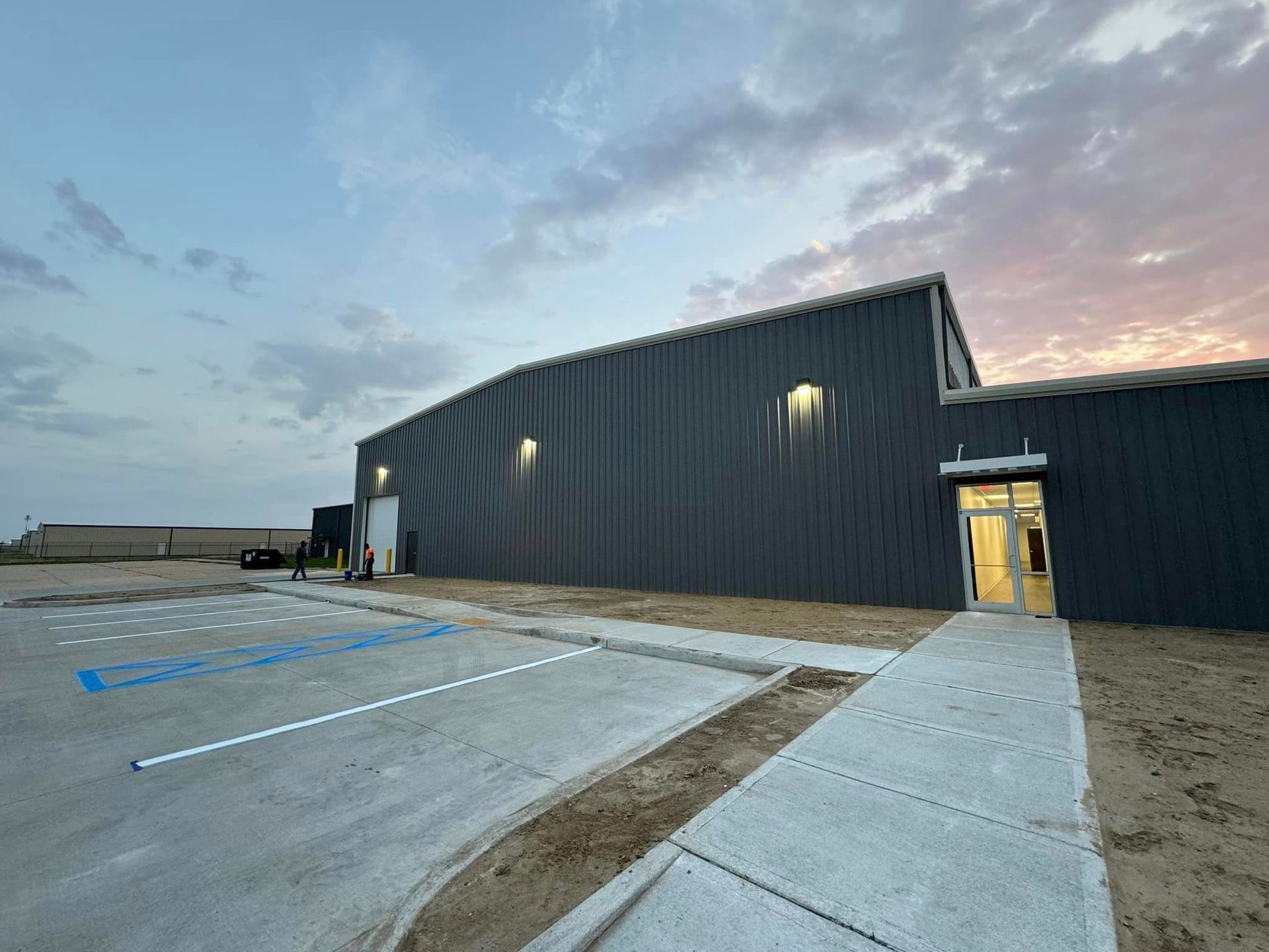 A large building with a walkway leading to it and a parking lot in front of it.