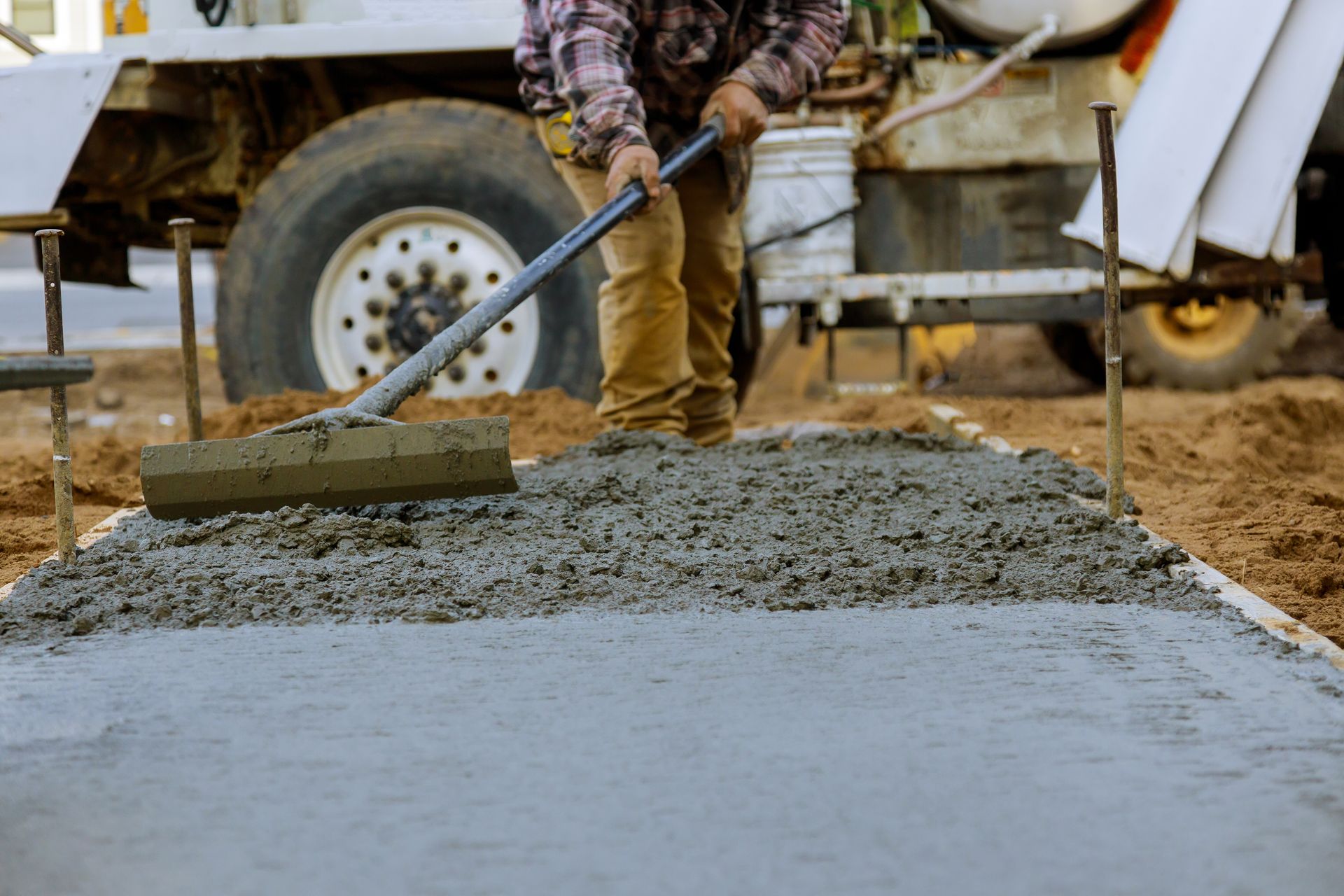 A man is raking concrete on a construction site.