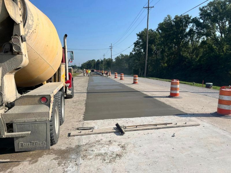 A concrete truck is pouring concrete on a road.