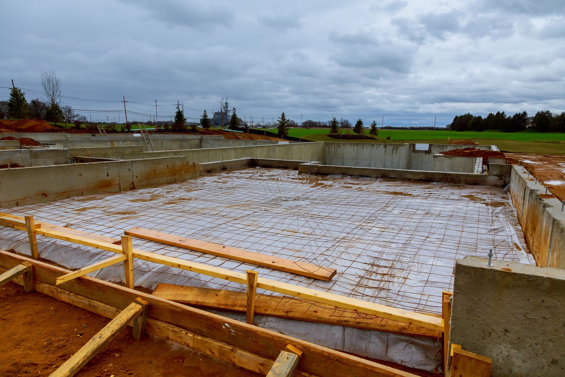 A concrete foundation for a house is being built on a cloudy day.