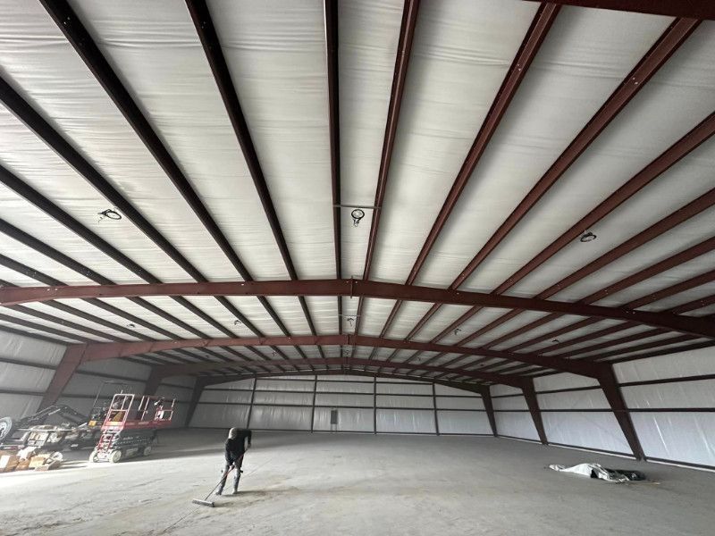 A man is standing inside of a large building with a vacuum cleaner.