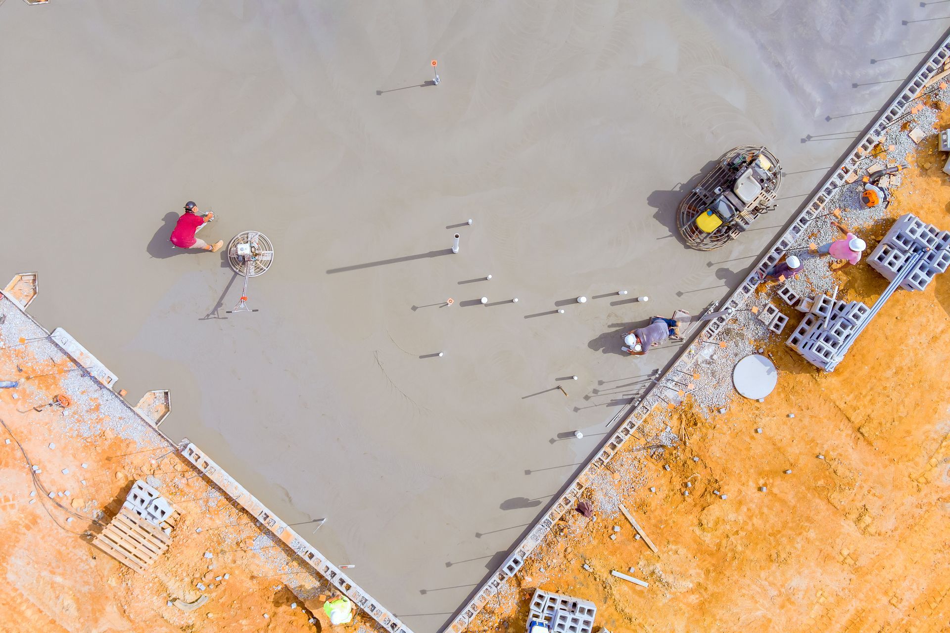 An aerial view of a construction site with workers laying concrete.
