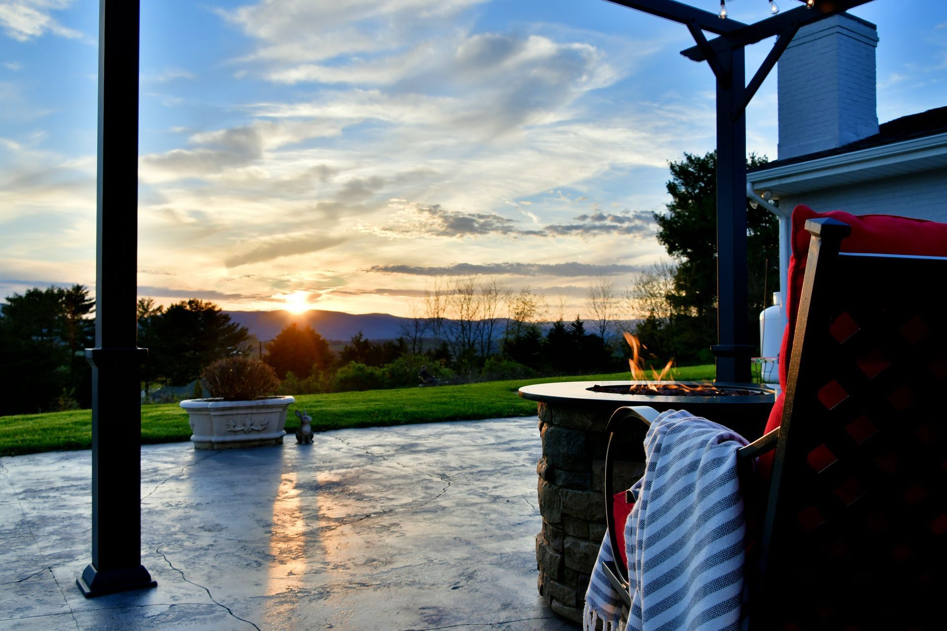 A patio with a fire pit and a sunset in the background