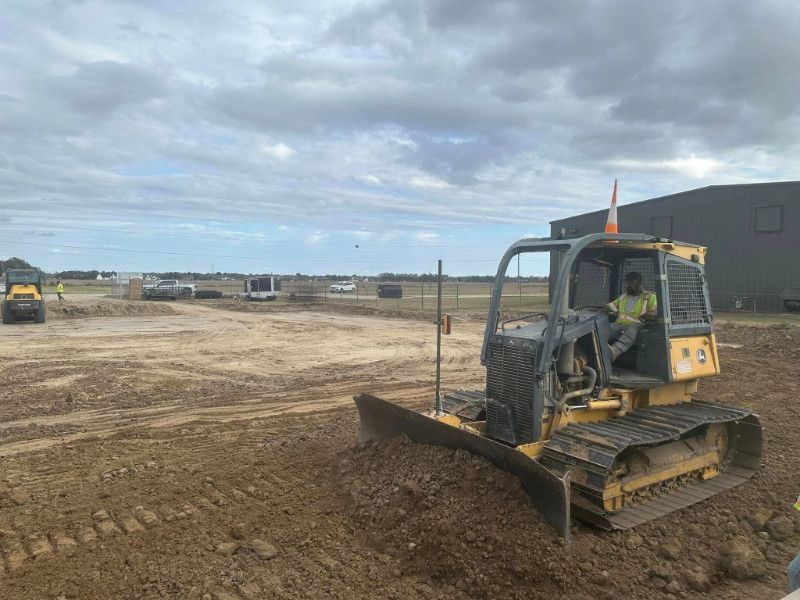 A man is driving a bulldozer in a dirt field.