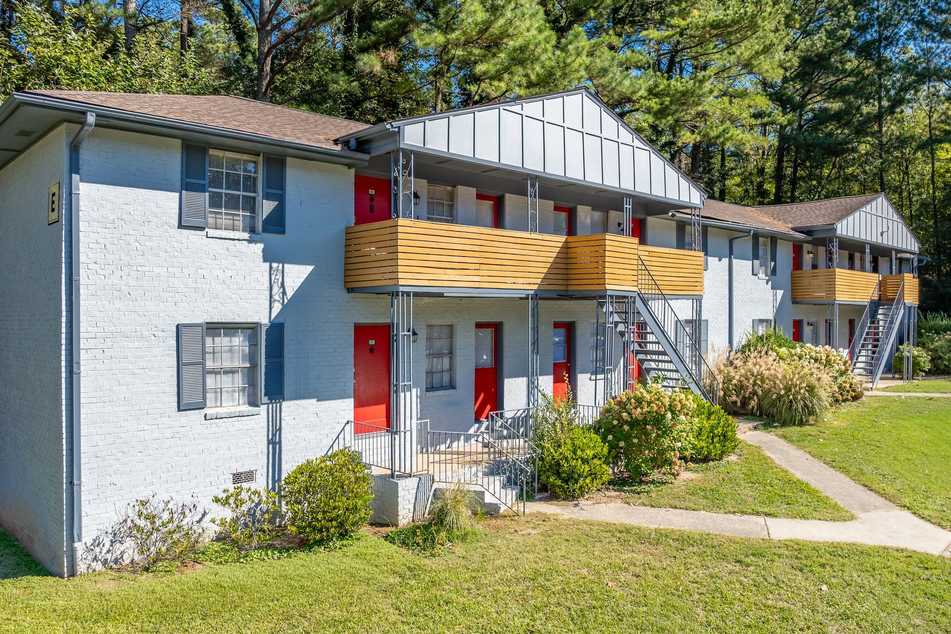 Brick building with white columns, door, and a brick walkway. Green lawn.