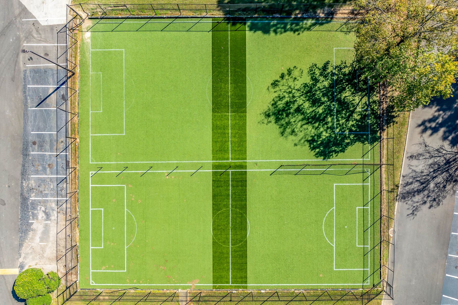 Overhead view of two soccer fields on green turf, divided by a dark green stripe.