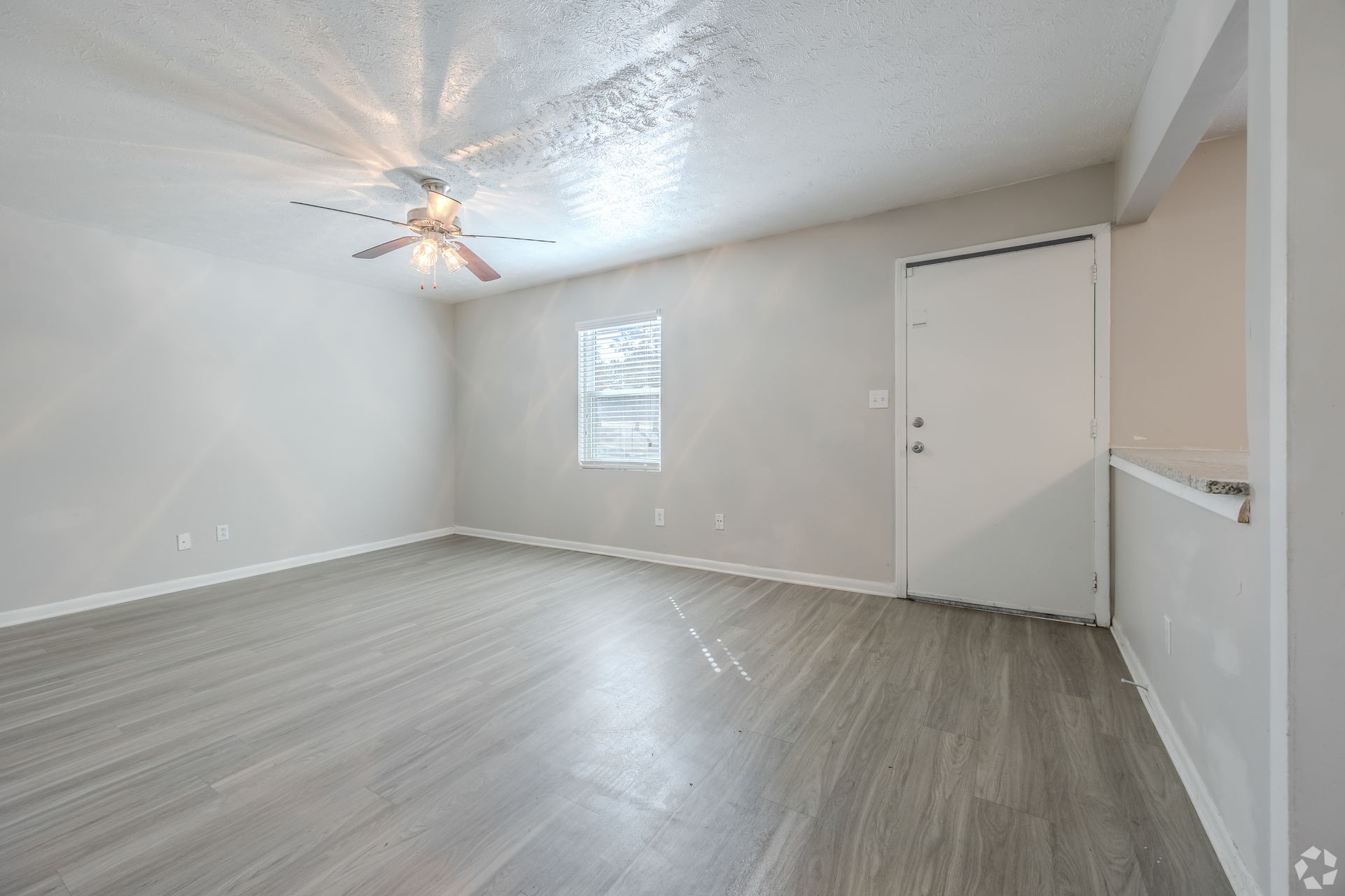 Dining area with glass table, chairs, artwork, and view into kitchen and living room.