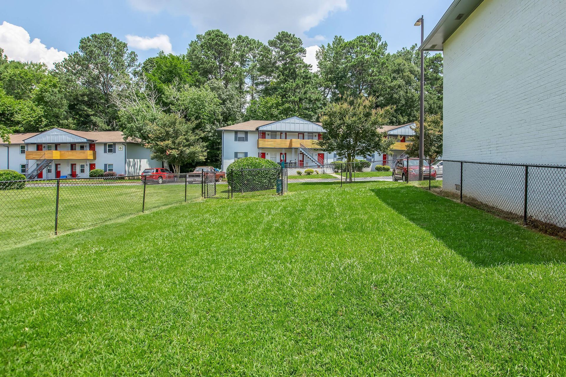 Grassy area with apartments in the background under a blue sky.