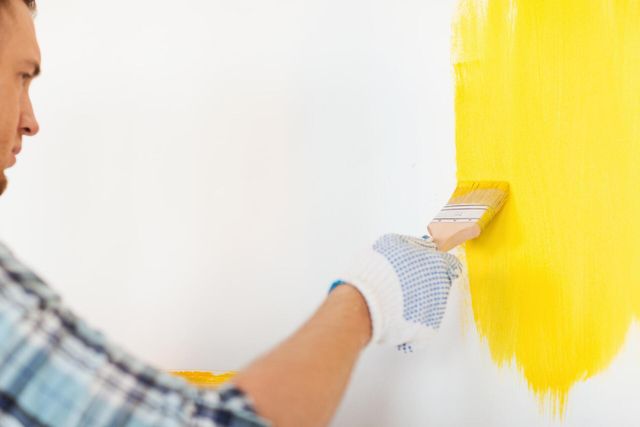 man painting the wall color yellow