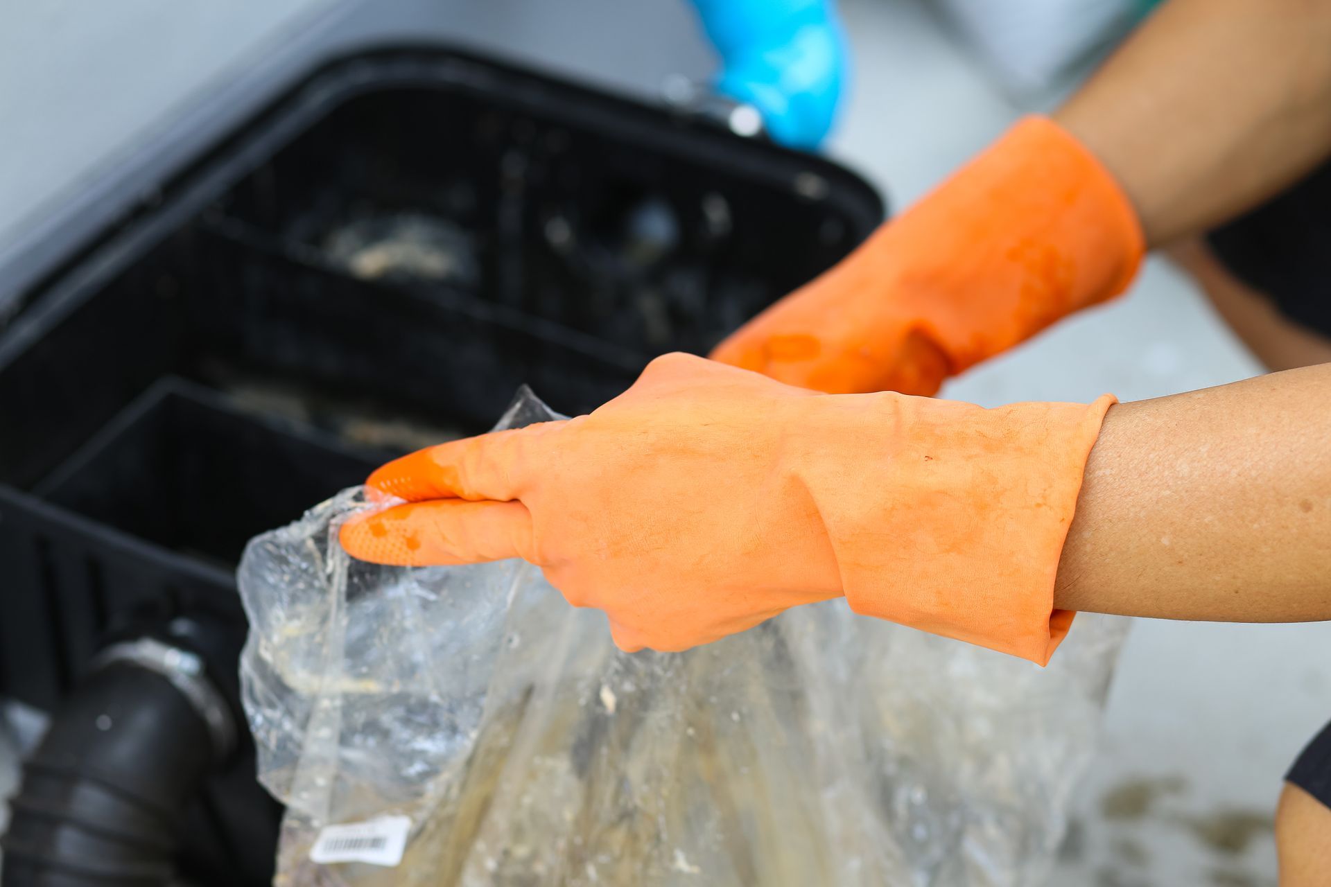 Man cleaning a grease traps box to maintain proper sanitation and prevent clogs.