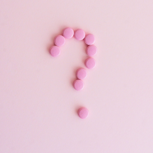 Pink question mark made of small beads on a pale pink background