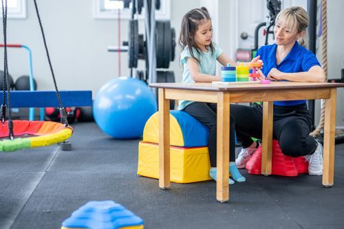 A Woman And A Little Girl Are Sitting At A Table In A Gym Playing With Toys - Valdosta, GA - Compass