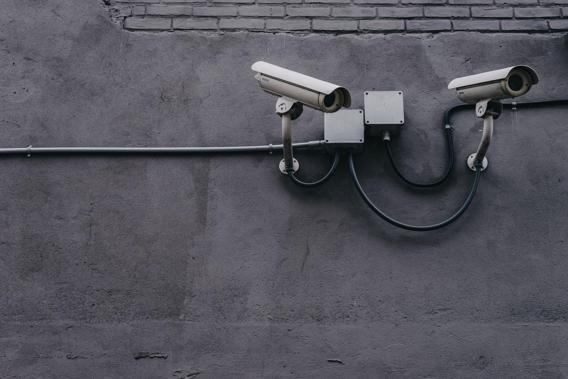 two security cameras are attached to a brick wall