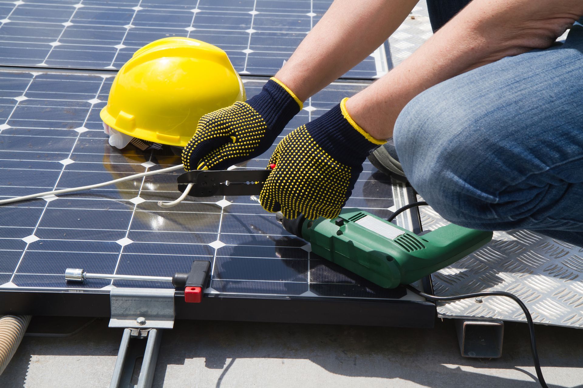 A person wearing gloves is working on a solar panel