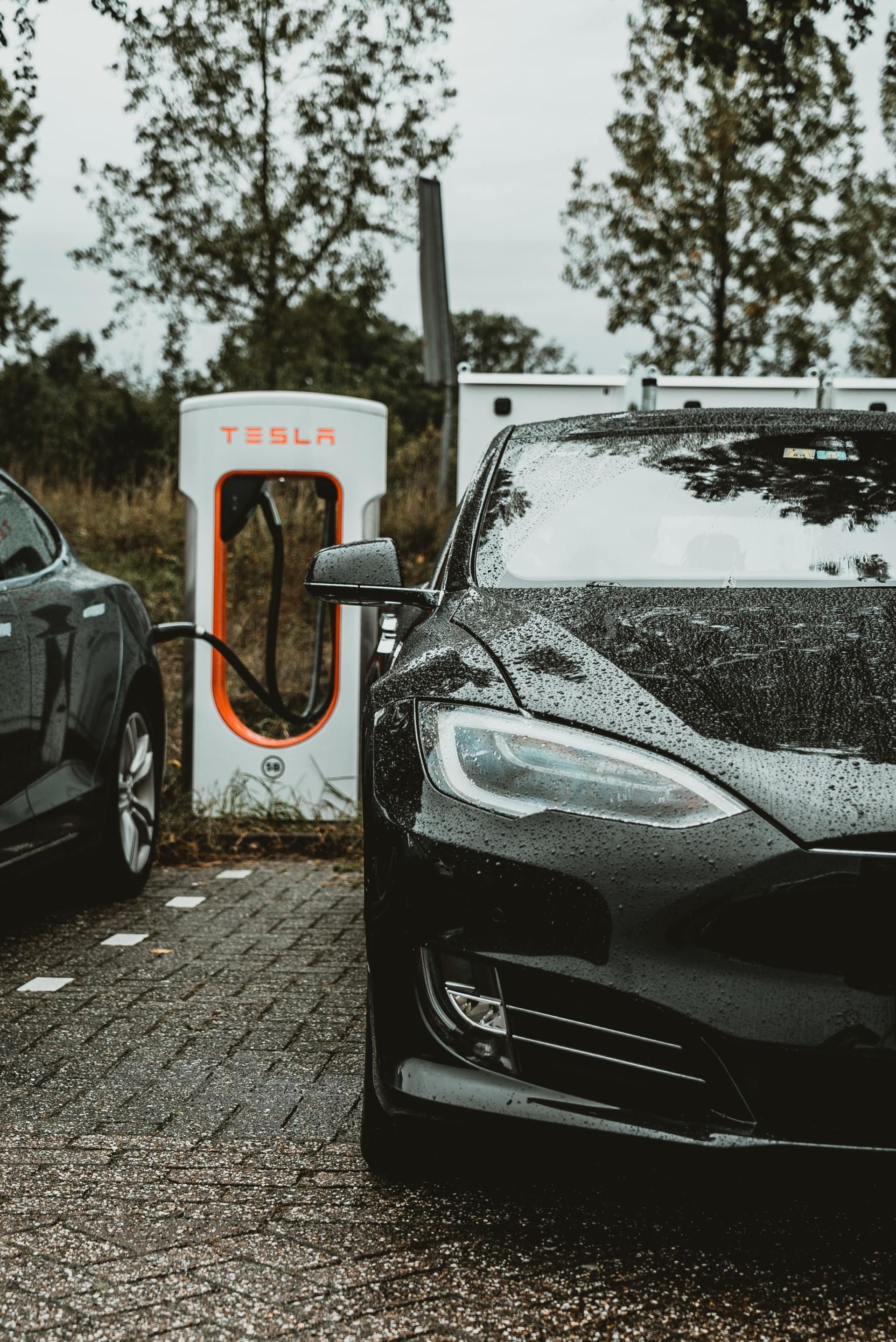 two tesla cars are charging at a tesla charging station