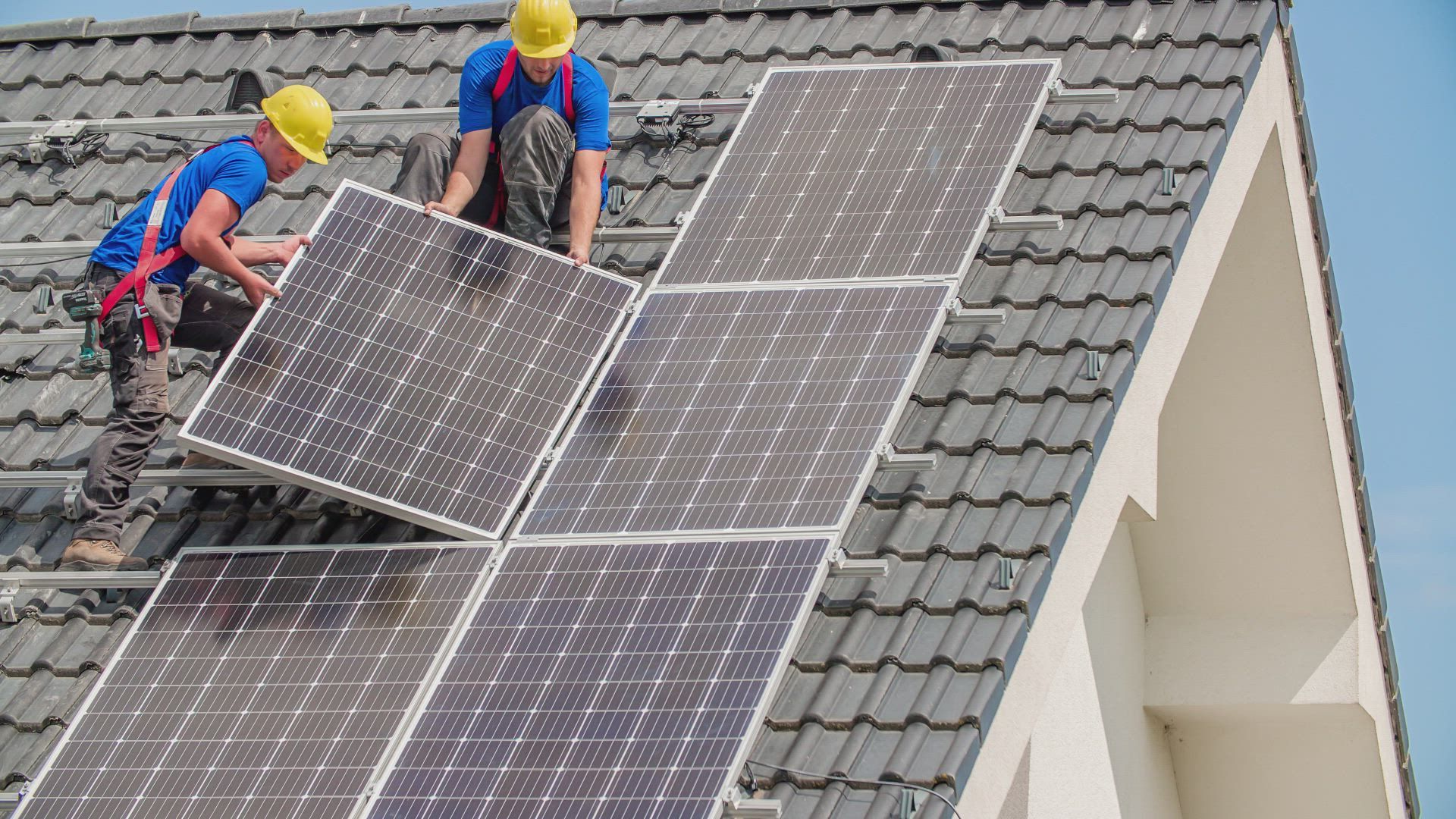 two men are installing solar panels on the roof of a house