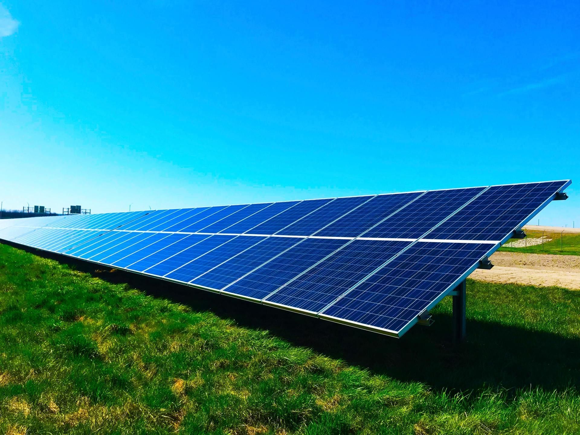 a row of solar panels in a grassy field