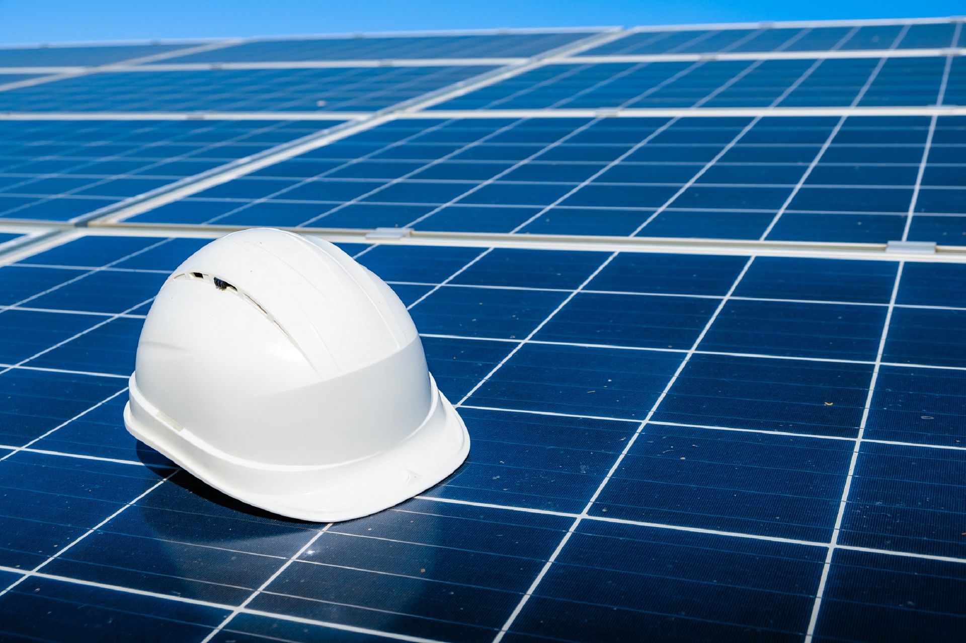 a white hard hat sits on top of a solar panel