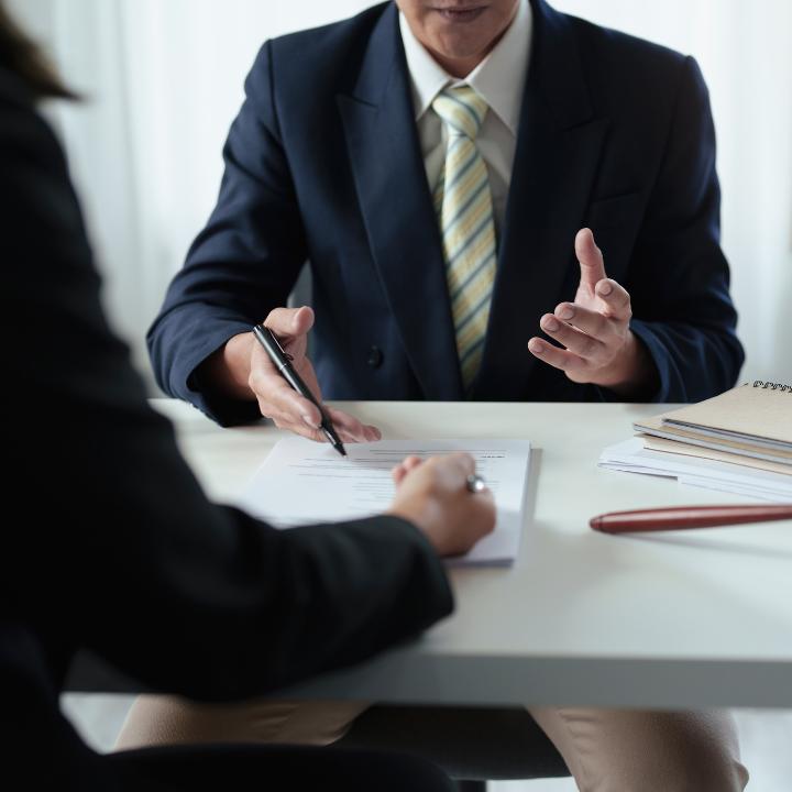 A man in a suit and tie is sitting at a table talking to a woman