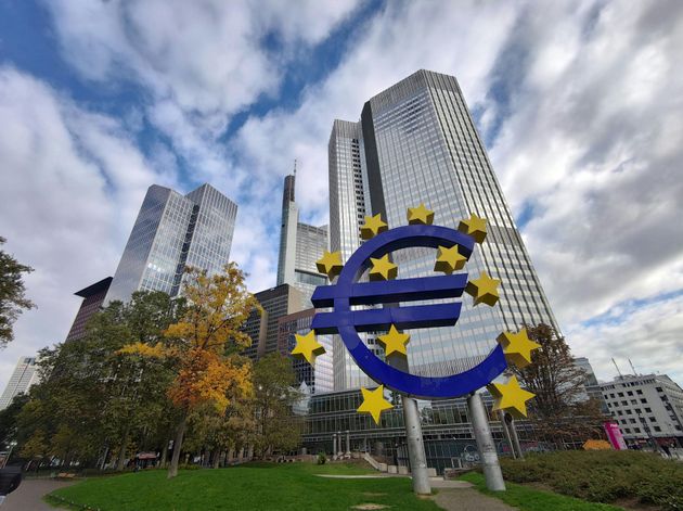 A large statue of a euro sign in front of tall buildings