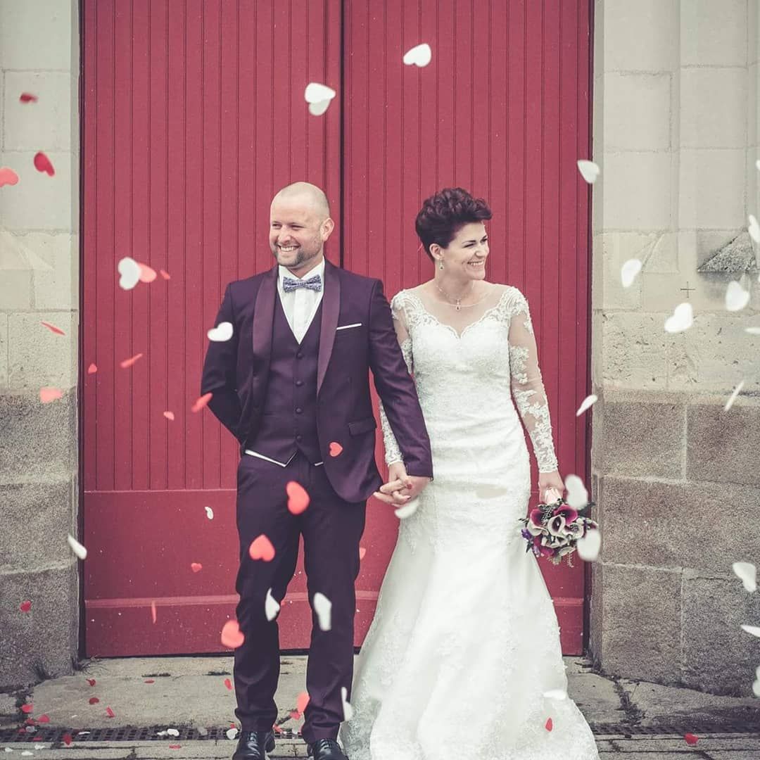 Une mariée et un marié posent pour une photo devant une porte rouge.