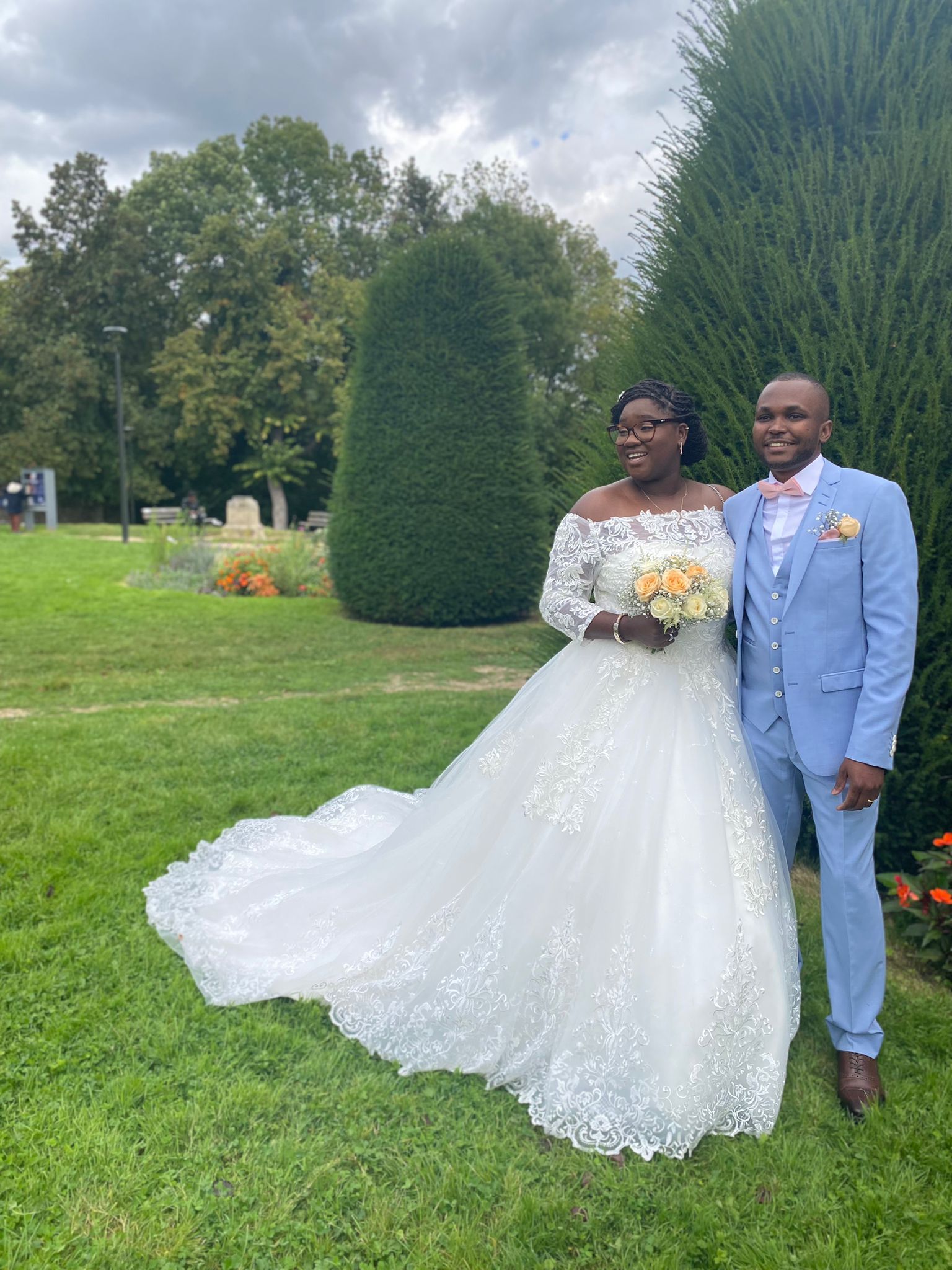 Une mariée et un marié posent pour une photo dans un parc.