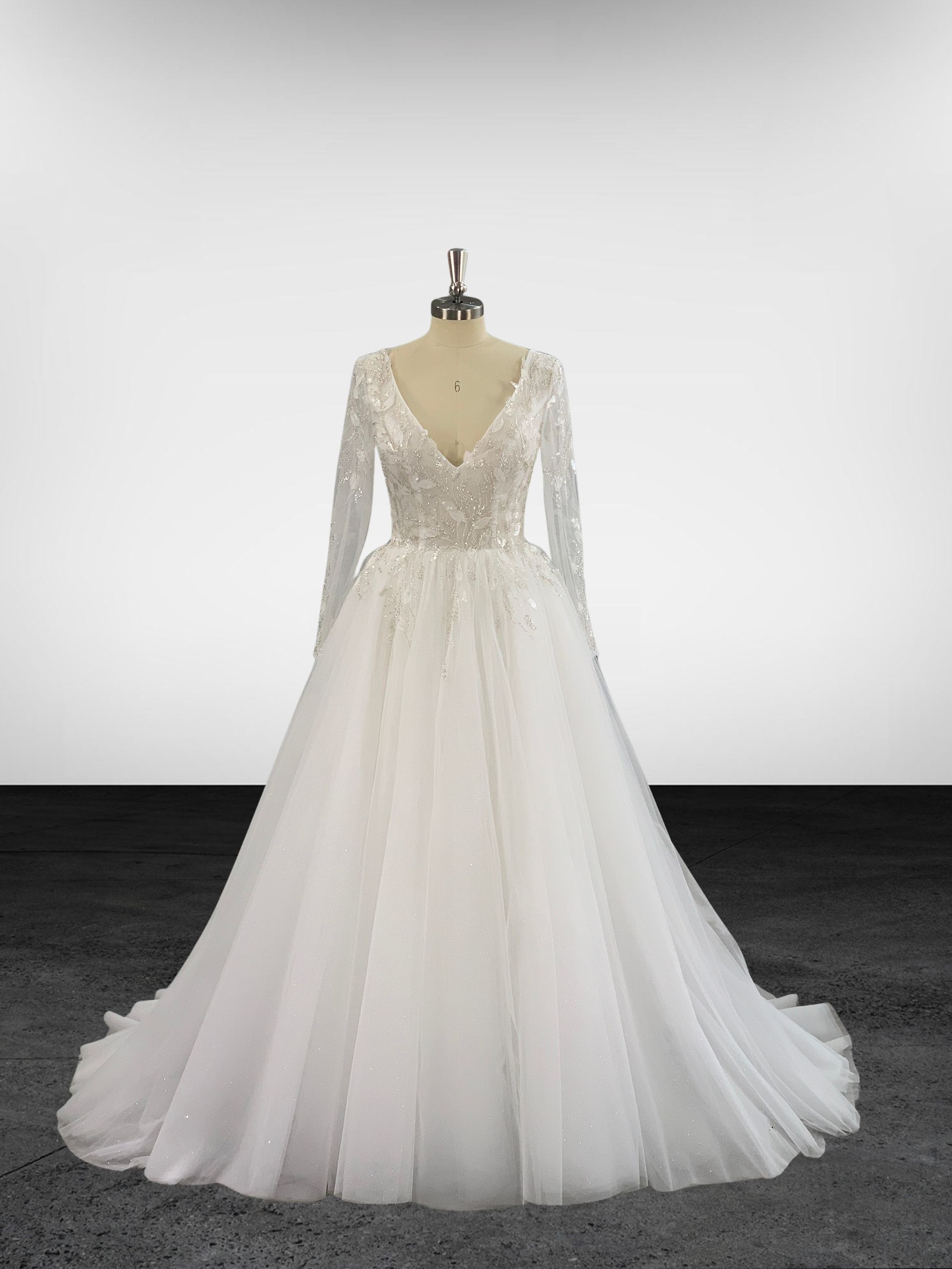 Une robe de mariée blanche à manches longues est sur un mannequin.