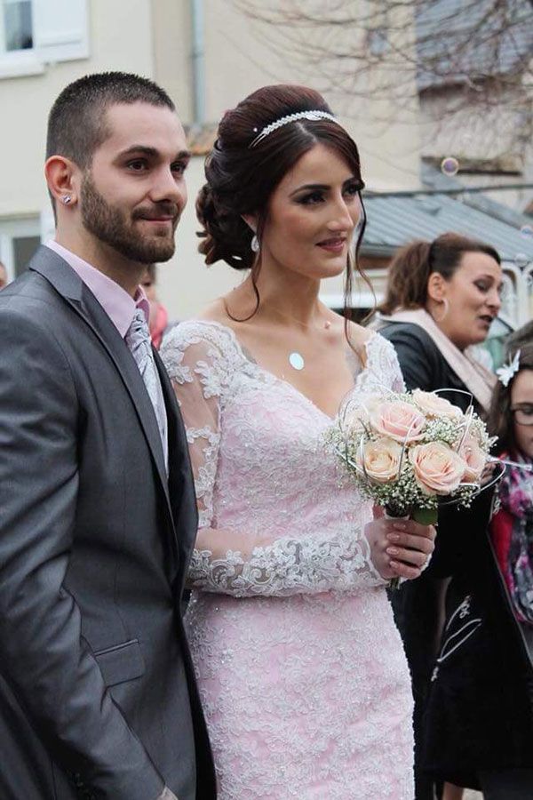 Une mariée et un marié posent pour une photo tandis que la mariée tient un bouquet de fleurs.