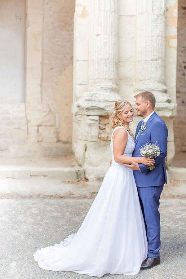 Une mariée et un marié posent pour une photo devant un bâtiment.
