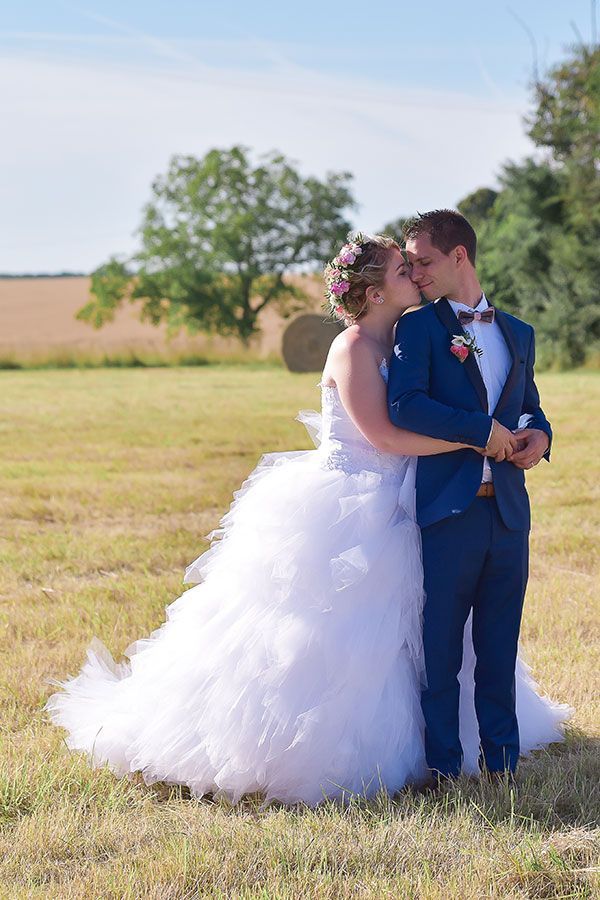 Une mariée et un marié s'embrassent dans un champ.